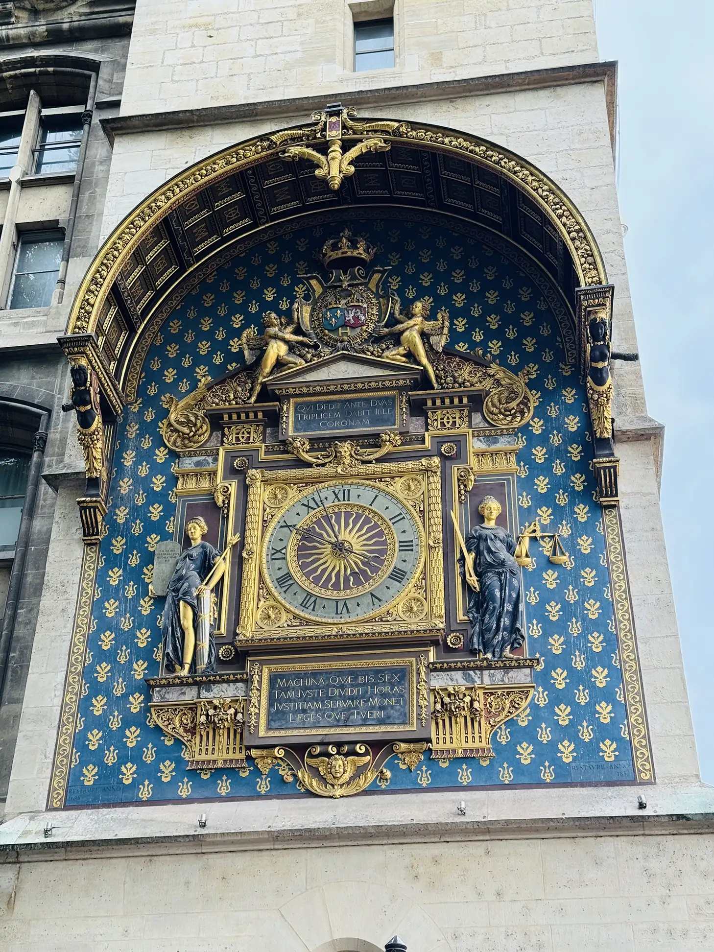 Close-up of the ornate gilded Tour de l'Horloge clock face with statues of Law and Justice on the Conciergerie
