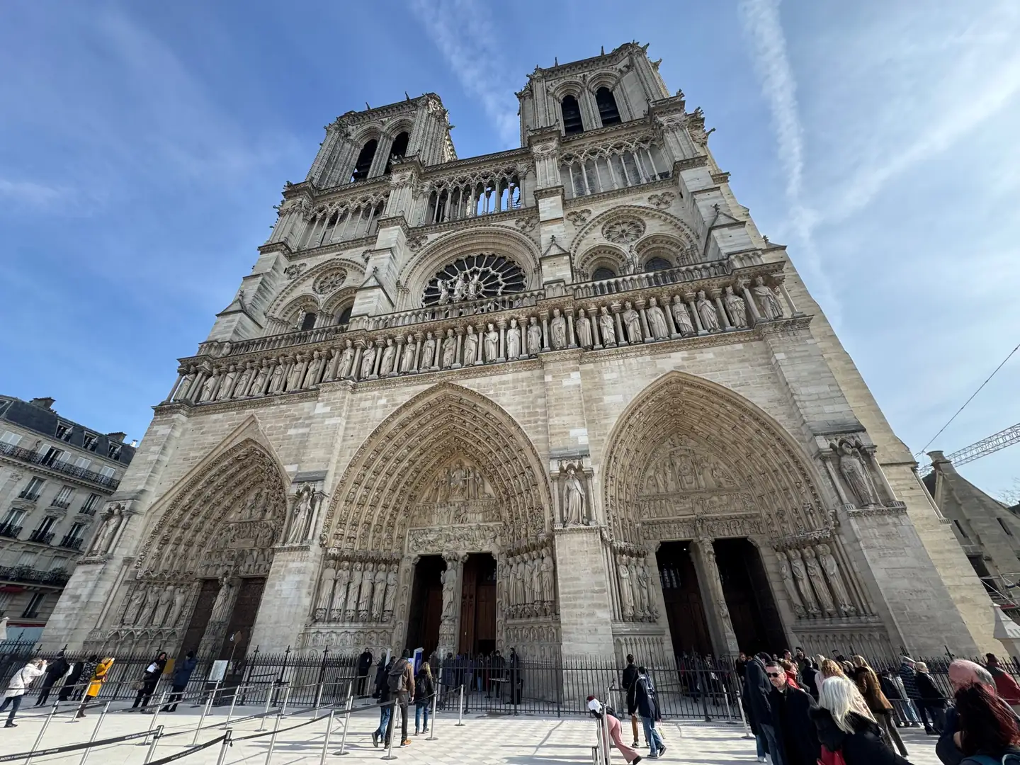West façade of Notre-Dame de Paris with its twin towers, Gallery of Kings and three carved portals under a blue sky